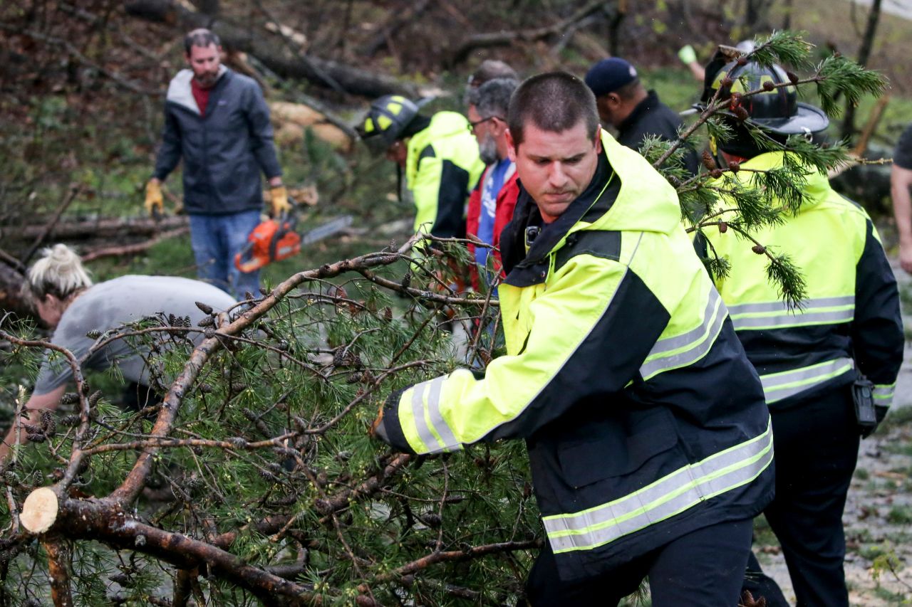 A firefighter works with Eagle Point residents to remove fallen trees blocking roads.