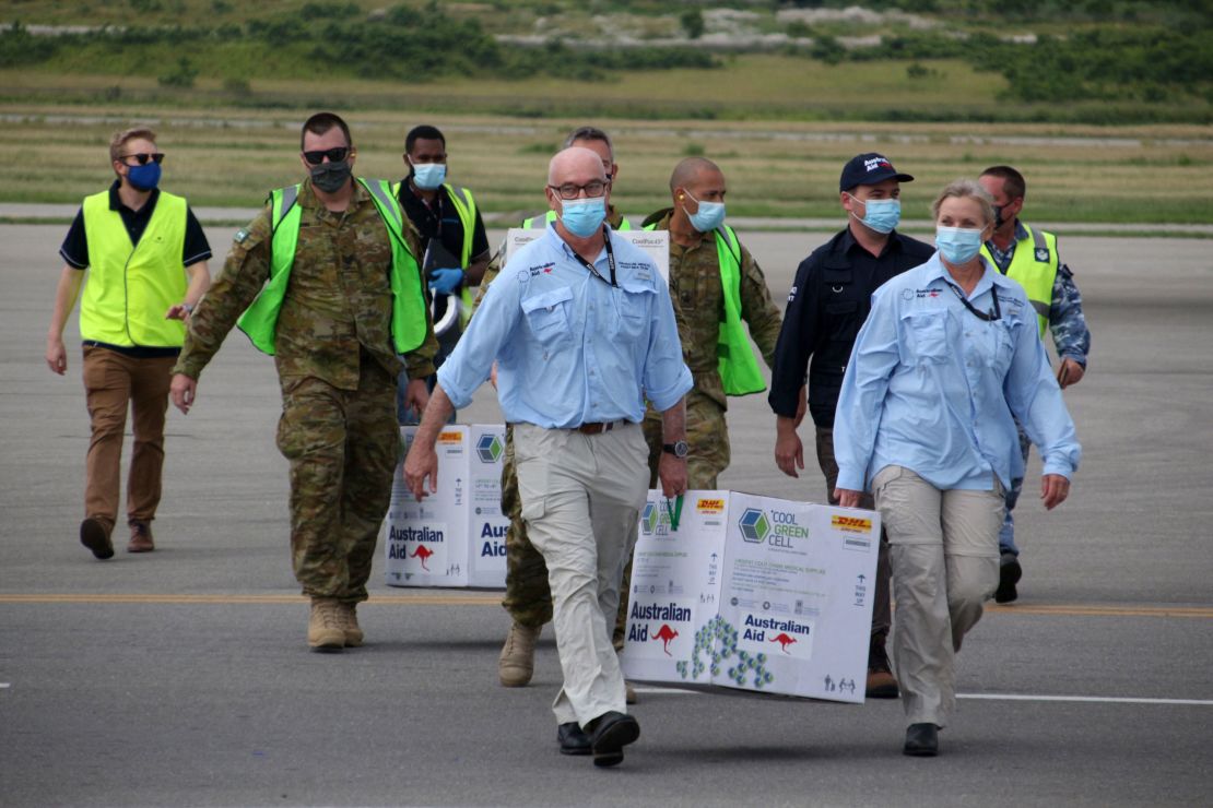 Australian officials carry boxes containing some 8,000 initial doses of the AstraZeneca vaccine at the Port Moresby international airport on March 23.