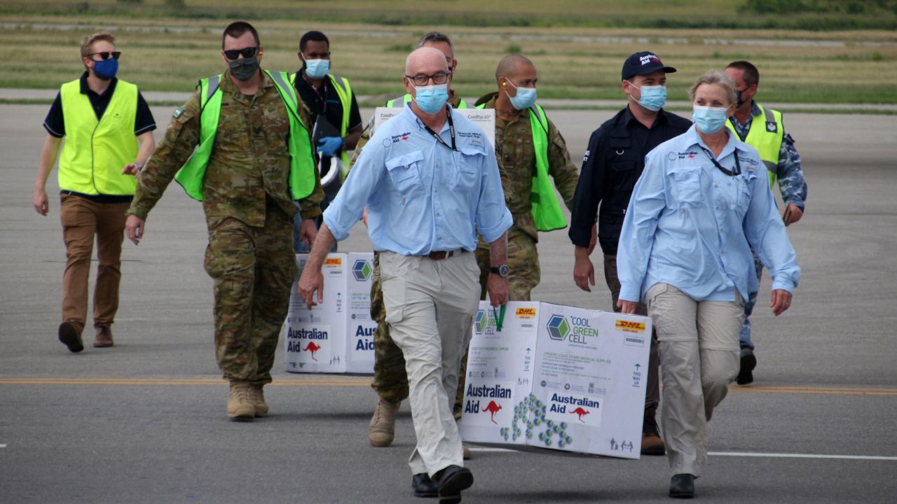 Australian officials carry boxes containing some 8,000 initial doses of the AstraZeneca vaccine at the Port Moresby international airport on March 23. 