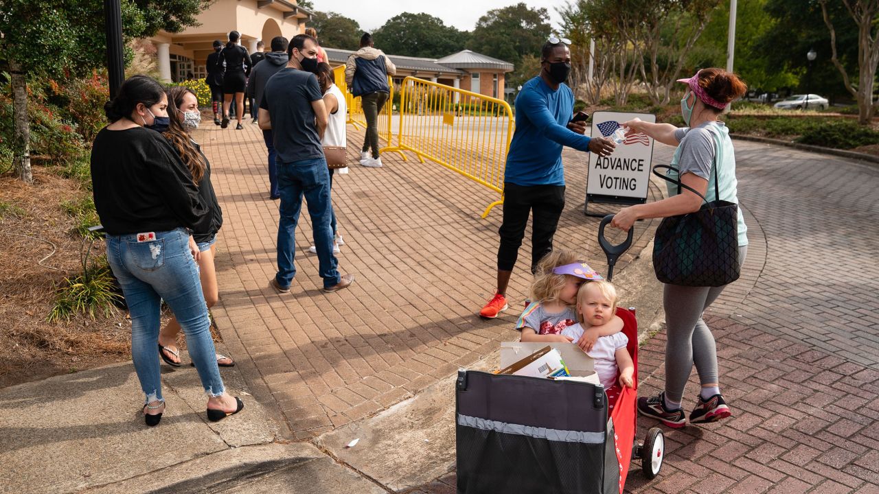 Megan Dominy pulls Lila Taylor(L), 4, and Brielle Taylor, 1, while offering water and snacks to people waiting in line to cast their ballots at an early voting location in the Smyrna Community Center on October 24, 2020, in Smyrna, Georgia. - Neighbors and volunteers are handing out water and snacks to the masked voters waiting patiently in line to cast their ballots on a hot October day in the Atlanta suburb of Smyrna.
Americans go to the polls on November 3 but the enthusiastic early voting here has already given the morning an air of Election Day.
Georgia has been a reliably Republican, conservative bastion and a Democrat has not won in the Peach State since Bill Clinton, a fellow Southerner, in 1992.
But Democratic candidate Joe Biden, 77, and Republican incumbent Donald Trump, 74, are running neck-and-neck in the polls in Georgia. (Photo by Elijah Nouvelage / AFP) (Photo by ELIJAH NOUVELAGE/AFP via Getty Images)