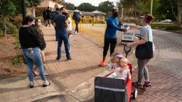 Megan Dominy pulls Lila Taylor(L), 4, and Brielle Taylor, 1, while offering water and snacks to people waiting in line to cast their ballots at an early voting location in the Smyrna Community Center on October 24, 2020, in Smyrna, Georgia. - Neighbors and volunteers are handing out water and snacks to the masked voters waiting patiently in line to cast their ballots on a hot October day in the Atlanta suburb of Smyrna.Americans go to the polls on November 3 but the enthusiastic early voting here has already given the morning an air of Election Day.Georgia has been a reliably Republican, conservative bastion and a Democrat has not won in the Peach State since Bill Clinton, a fellow Southerner, in 1992.But Democratic candidate Joe Biden, 77, and Republican incumbent Donald Trump, 74, are running neck-and-neck in the polls in Georgia. (Photo by Elijah Nouvelage / AFP) (Photo by ELIJAH NOUVELAGE/AFP via Getty Images)