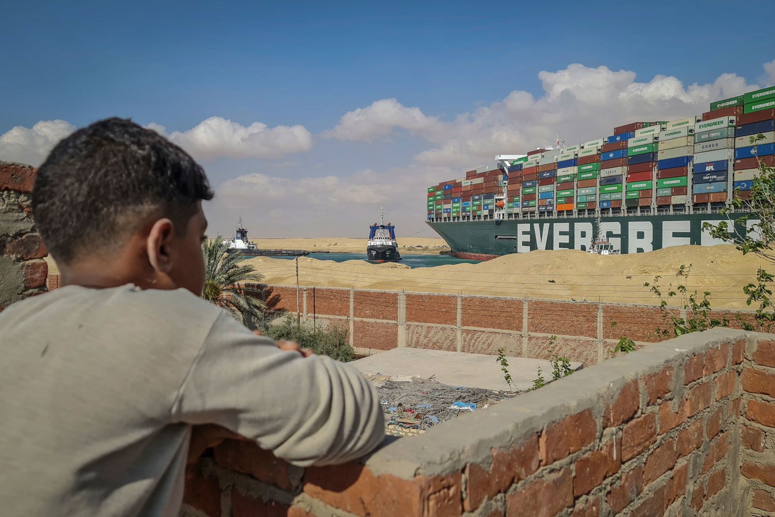 A boy watches a couple of tugboats trying to free the Ever Given on Friday.