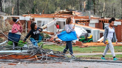 People make their way down a debris-filled street in Coweta County, Georgia, on Friday.