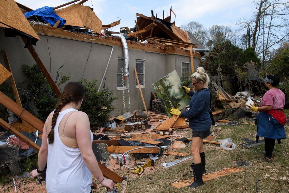 A volunteer picks up artwork a day after a tornado hit the Eagle Point neighborhood south of Birmingham, Alabama.