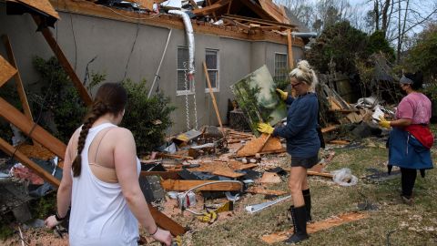 A volunteer picks up artwork a day after a tornado hit the Eagle Point neighborhood south of Birmingham, Alabama.