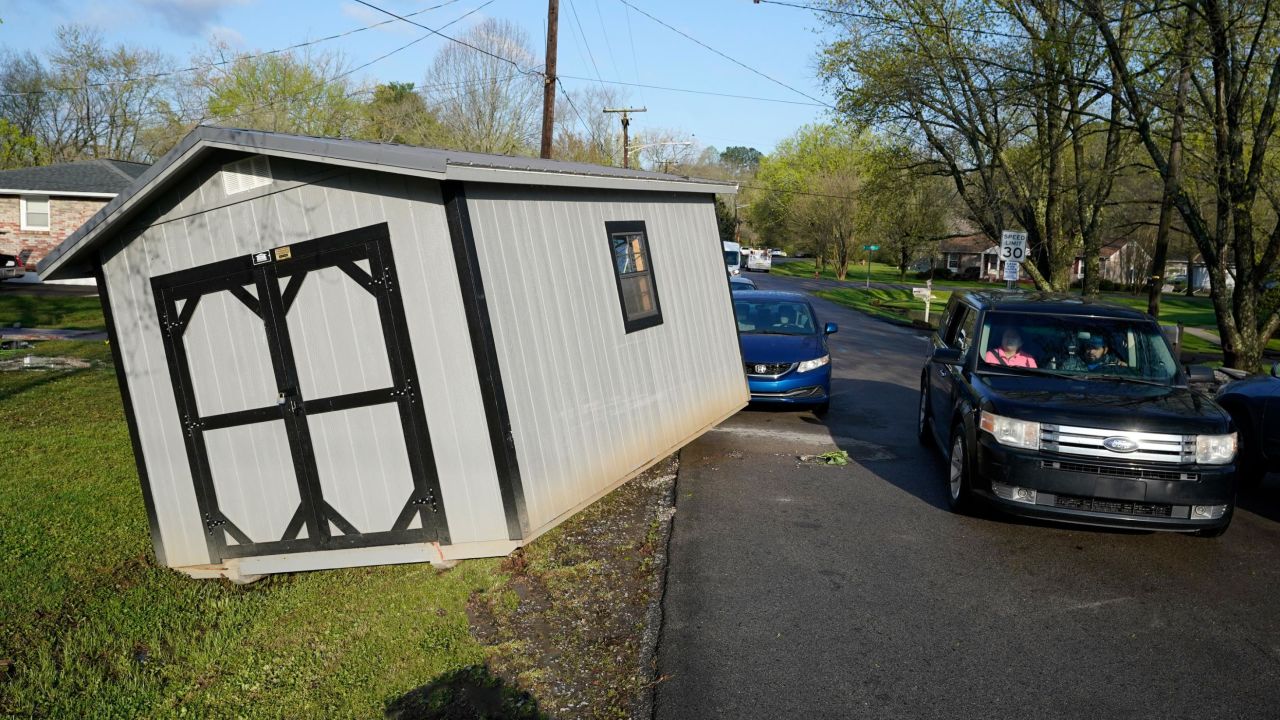 A car passes a utility shed on Sunday that was carried onto a street by floodwaters in Nashville.