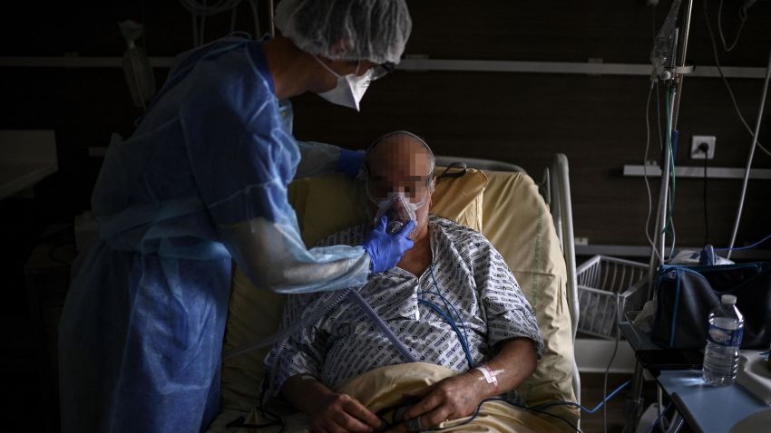 A member of the medical staff places a ventilation device on a Covid-19 patient, in a room of the pneumology unit of the AP-HP Cochin hospital, in Paris on March 18, 2021 as the number of people hospitalised with the Covid-19 is on the rise in the French capital. - From pneumology unit to the intensive care one, the Covid-19 is again overflowing Cochin hospital, where members of the medical staff are already thinking about a dark scenario. (Photo by Christophe ARCHAMBAULT / AFP) (Photo by CHRISTOPHE ARCHAMBAULT/AFP via Getty Images)