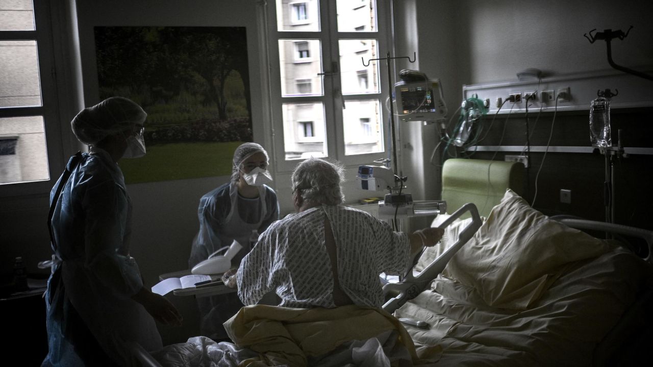 Nurses help a Covid-19 patient sitting in his bed, in a room, of the pneumology unit of the AP-HP Cochin hospital, in Paris on March 18, 2021.