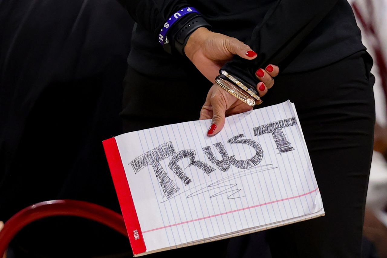 A Louisville coach holds a sign that says "trust" during the Sweet Sixteen game against Oregon. Louisville won 60-42.