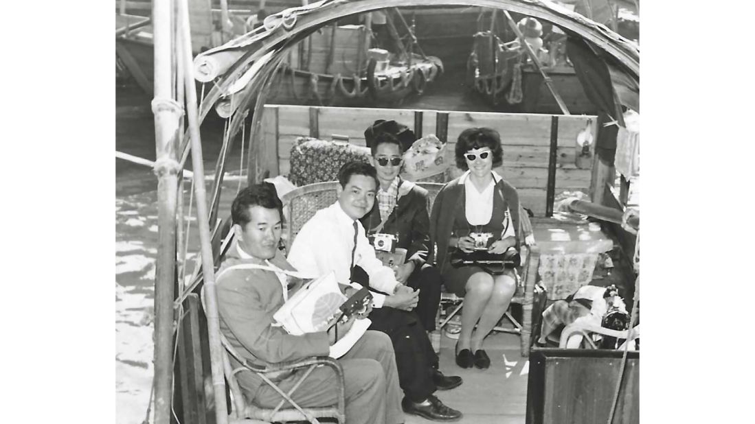 <strong>On the job in Hong Kong: </strong>In this old photo<strong>,</strong> Fong sits on a sampan boat with some travelers in the city's Aberdeen neighborhood. He says they were heading to Jumbo Kingdom and Tai Pak -- Hong Kong's famed floating restaurant.