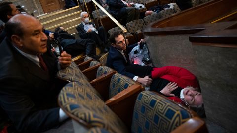 US Rep. Jason Crow comforts Rep. Susan Wild while taking cover as protesters disrupt the joint session of Congress to certify the Electoral College vote on January 6, 2021. 