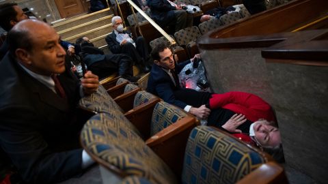 US Rep. Jason Crow comforts Rep. Susan Wild while taking cover as protesters disrupt the joint session of Congress to certify the Electoral College vote on January 6, 2021.