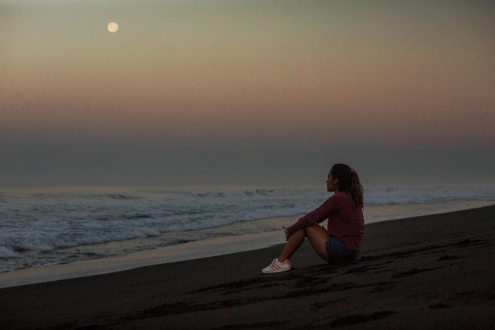 A women watches the moon during a sunrise at Monterrico beach in Santa Rosa, Guatemala, on Monday.