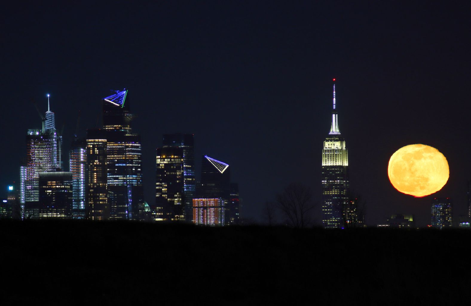 The worm moon is seen from Kearny, New Jersey, as it rises behind the Empire State Building and Hudson Yards in New York City.