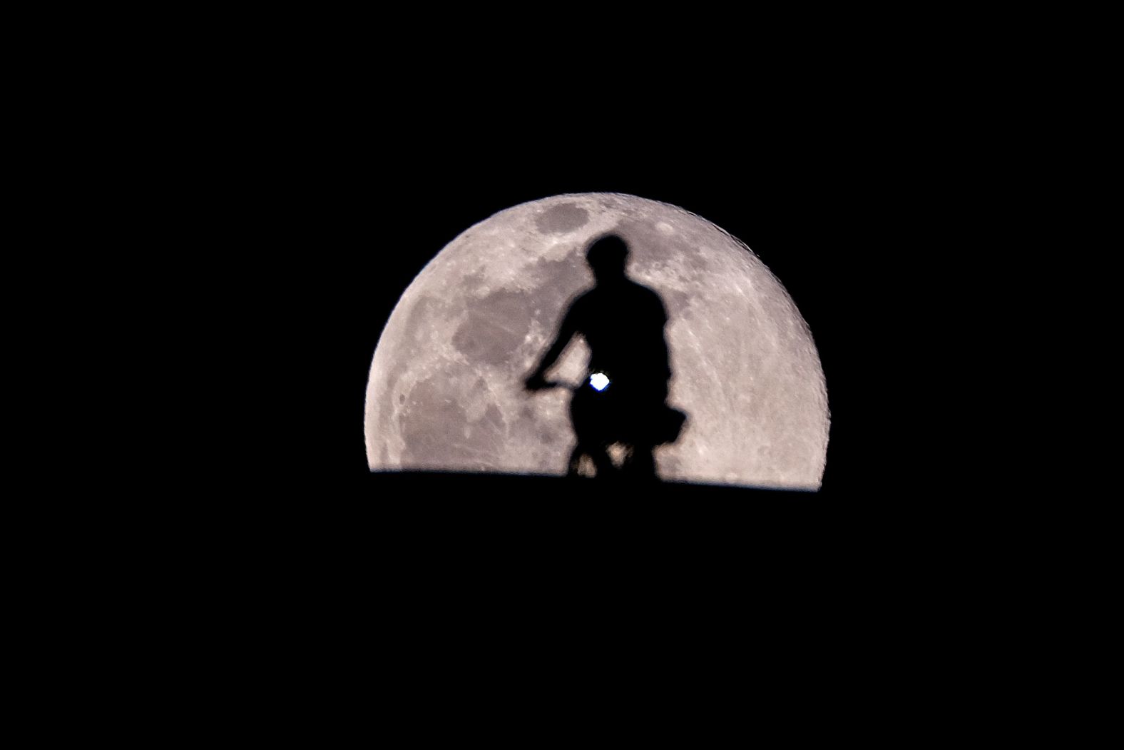 A cyclist in Los Angeles, California is silhouetted against the backdrop of the "Worm Moon".