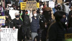 A man holds a sign that reads "Racism is a Virus" during the "We Are Not Silent" rally against anti-Asian hate in response to recent anti-Asian crime in the Chinatown-International District of Seattle, Washington on March 13, 2021. - Reports of attacks, primarily against Asian-American elders, have spiked in recent months -- fuelled, activists believe, by talk of the "Chinese virus" by former president Donald Trump and others. (Photo by Jason Redmond / AFP) (Photo by JASON REDMOND/AFP via Getty Images)