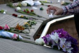 A visitor places a candle among flowers at the Columbine Memorial at Clement Park in Littleton, Colorado, during a community vigil for the 20th anniversary of the Columbine High School mass shooting on April 19, 2019. - 12 students and one teacher were massacred by two heavily armed students nearly 20 years ago during the Columbine High School shooting on April 20, 1999. (Photo by Jason Connolly / AFP) (Photo by JASON CONNOLLY/AFP via Getty Images)