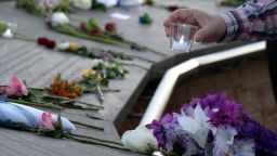 TOPSHOT - A visitor places a candle among flowers at the Columbine Memorial at Clement Park in Littleton, Colorado, during a community vigil for the 20th anniversary of the Columbine High School mass shooting on April 19, 2019. - 12 students and one teacher were massacred by two heavily armed students nearly 20 years ago during the Columbine High School shooting on April 20, 1999. (Photo by Jason Connolly / AFP) (Photo by JASON CONNOLLY/AFP via Getty Images)