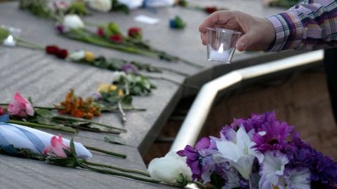 A visitor places a candle among flowers at the Columbine Memorial at Clement Park in Littleton, Colorado, during a community vigil for the 20th anniversary of the Columbine High School mass shooting on April 19, 2019. - 12 students and one teacher were massacred by two heavily armed students nearly 20 years ago during the Columbine High School shooting on April 20, 1999. (Photo by Jason Connolly / AFP) (Photo by JASON CONNOLLY/AFP via Getty Images)