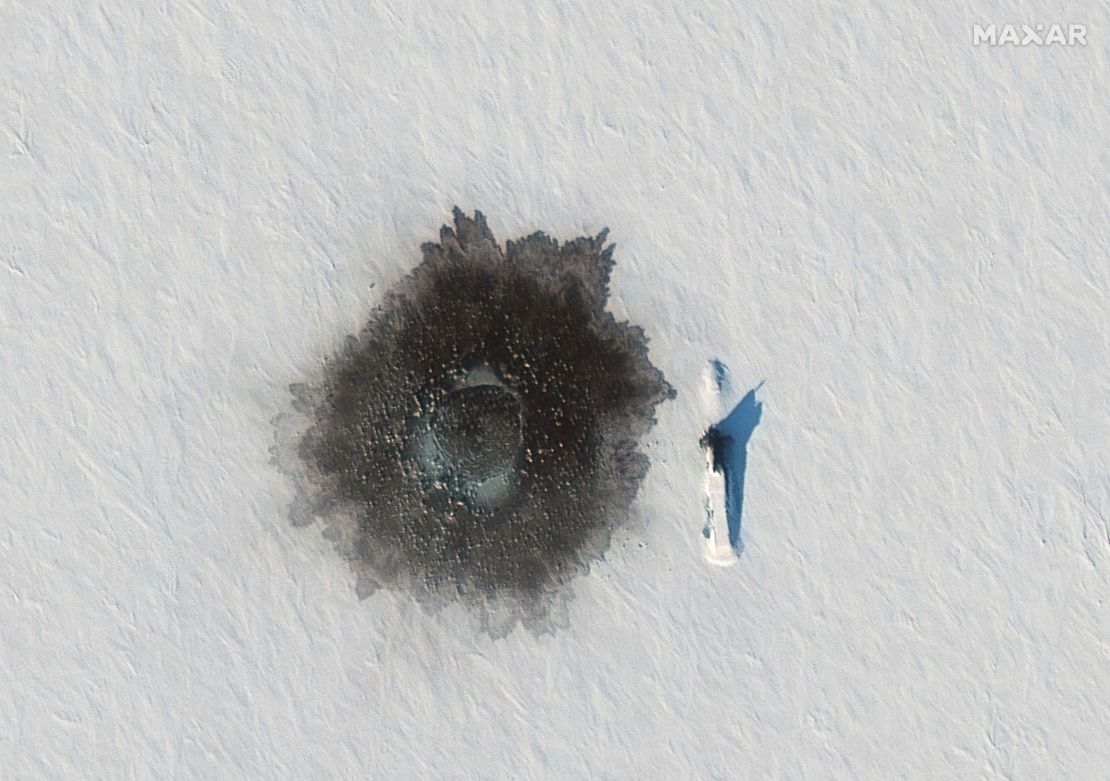 A Russian Delta IV submarine photographed on top of ice near Alexandra Island on March 27, during an exercise, with a likely hole blown in the ice to its left from underwater demolition.