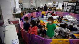 Young unaccompanied migrants, ages 3-9 watch TV inside a playpen at the Donna Department of Homeland Security holding facility, the main detention center for unaccompanied children in the Rio Grande Valley in Donna, Texas, March 30, 2021. CNN has blurred faces to protect individuals' identities.