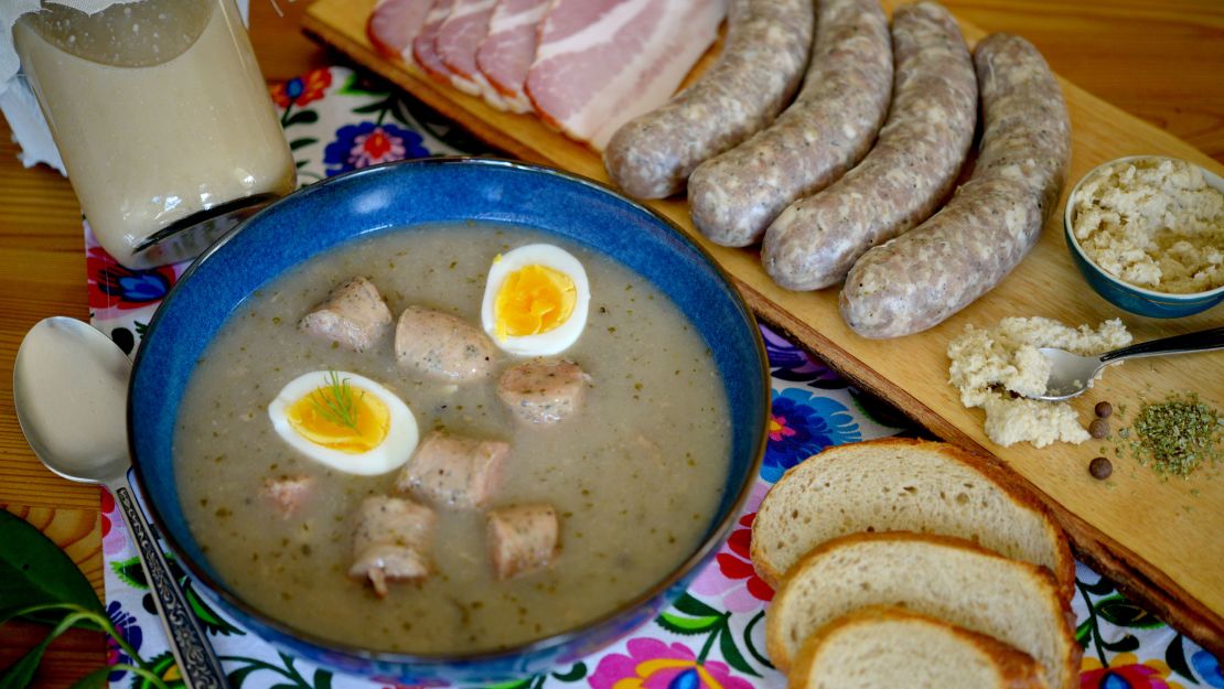 Das herzhafte polnische Gericht żurek oder saure Roggensuppe wird oft mit Wurst und einem gekochten Ei sowie Meerrettich für eine würzige Note serviert.