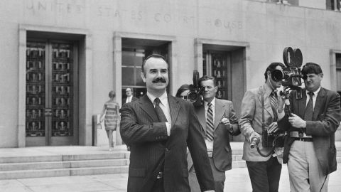 Former White House aide G. Gordon Liddy is filmed by journalists as he leaves US District Court, where he pleaded not guilty of breaking into Democratic National Headquarters at the Watergate Hotel.