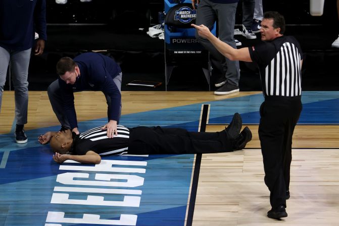 Referee Bert Smith lies on the court after <a href="index.php?page=&url=https%3A%2F%2Fwww.cnn.com%2F2021%2F03%2F30%2Fus%2Fncaa-gonzaga-usc-official-spt%2Findex.html" target="_blank">collapsing during the first half</a> of the Gonzaga-USC game. As he left the court on a gurney, he was sitting upright and appeared to be talking to a man walking beside him.