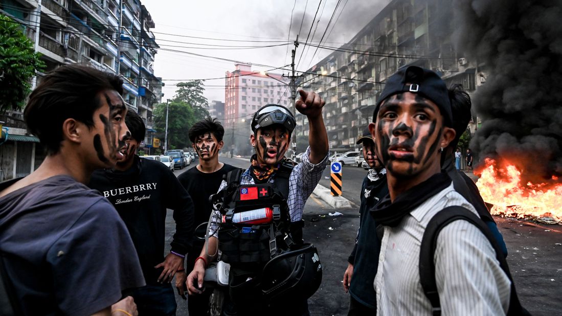 Protesters wearing face paint stand near a burning barricade during an anti-coup demonstration in Yangon on March 30.