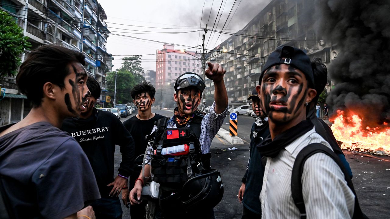 Protesters with their faces painted stand near a burning makeshift barricade during a protest against the military coup, in Yangon on Tuesday.