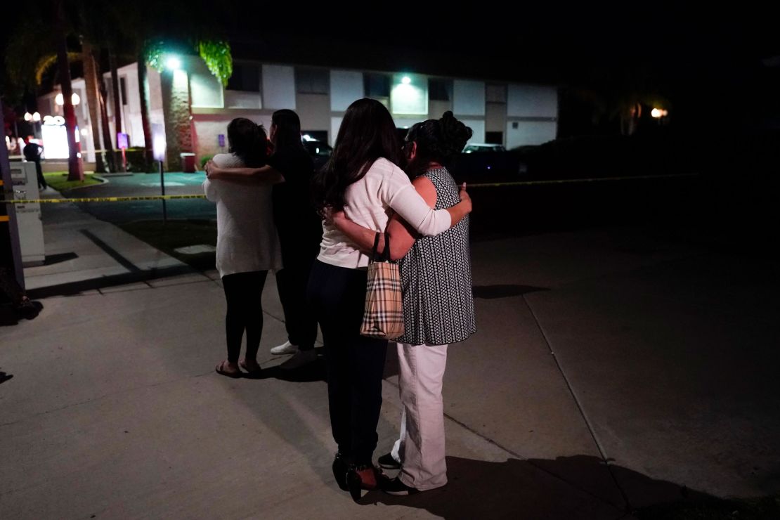 People comfort each other as they stand outside the Orange, California, business complex where the shooting occurred on Wednesday.