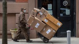 A UPS worker wheels packages near Washington Square Park on March 25, 2021 in New York City. After undergoing various shutdown orders for the past 12 months the city is currently in phase 4 of its reopening plan, allowing for the reopening of low-risk outdoor activities, movie and television productions, indoor dining as well as the opening of movie theaters, all with capacity restrictions. (Photo by Alexi Rosenfeld/Getty Images)