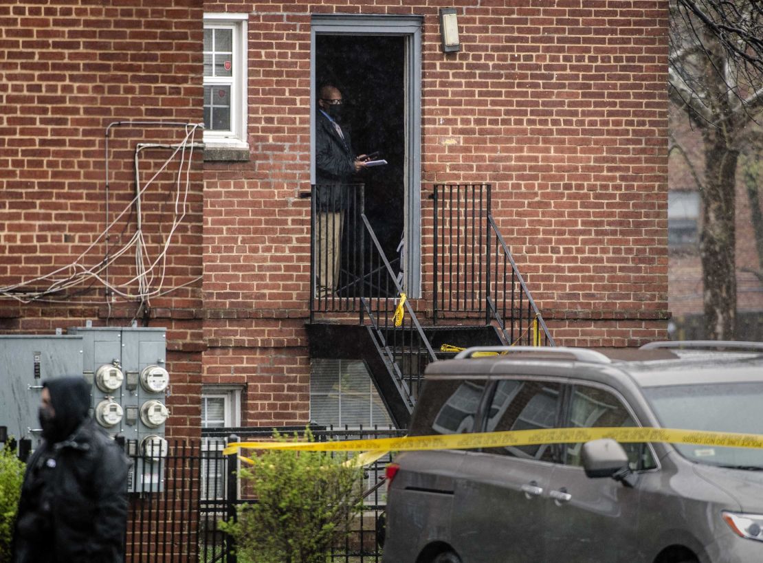 A detective stands in the doorway of a taped-off apartment building at the scene of a shooting in the Congress Heights area of Washington, DC, on Wednesday, March 31.