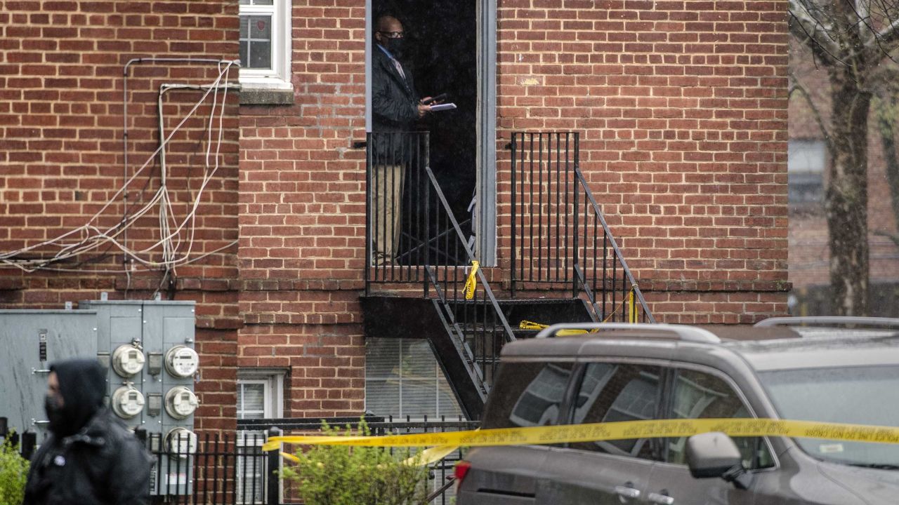 A detective stands in the doorway of a taped-off apartment building at the scene of a shooting in the Congress Heights area of Washington, DC, on Wednesday, March 31.