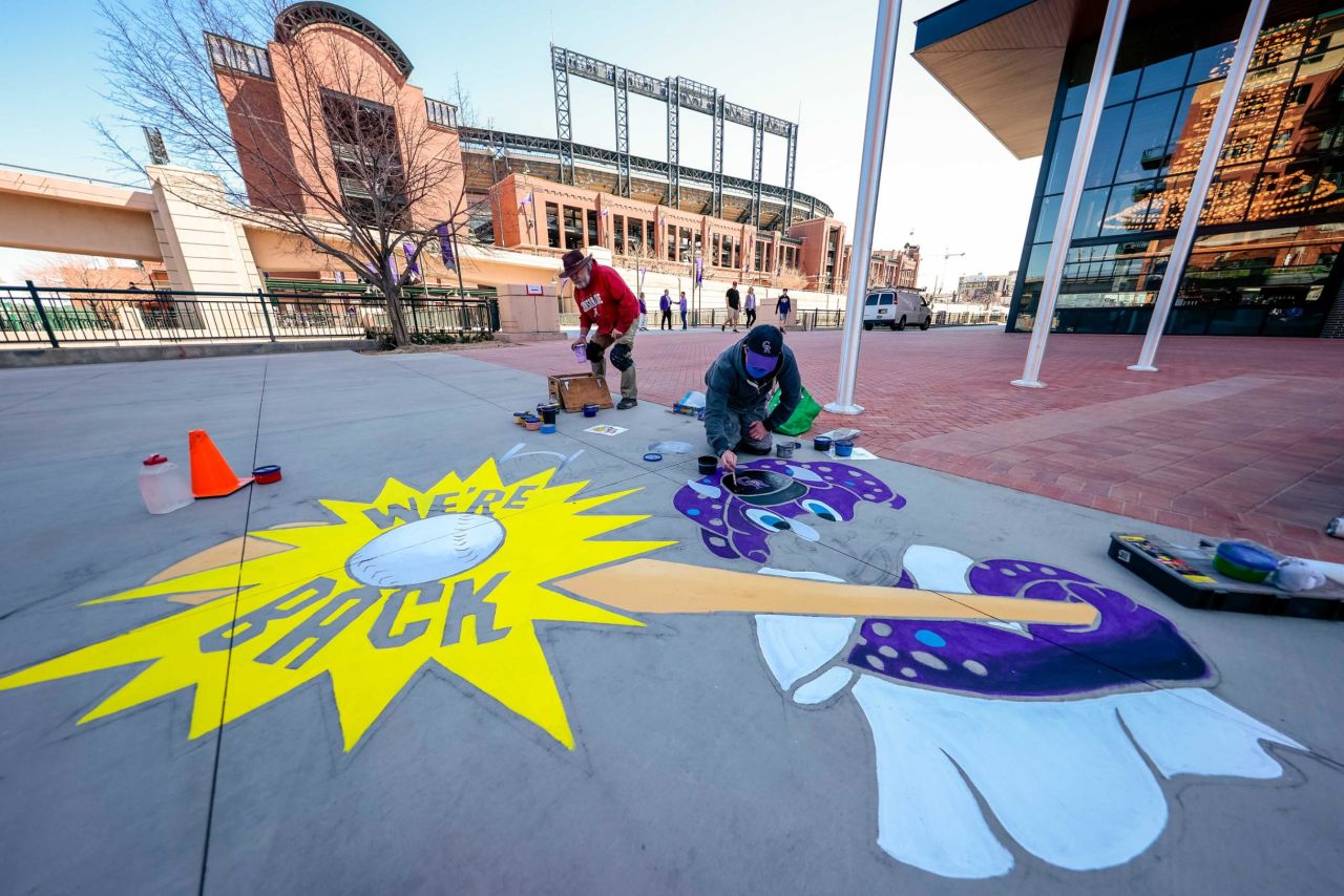 Artists Kyle Banister, left, and Eric Matelski paint a mural near Coors Field in Denver.