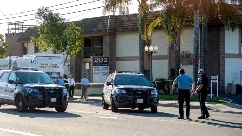 Officials work outside the Orange, California, business Thursday where four people, including a 9-year-old boy, were killed a day earlier.