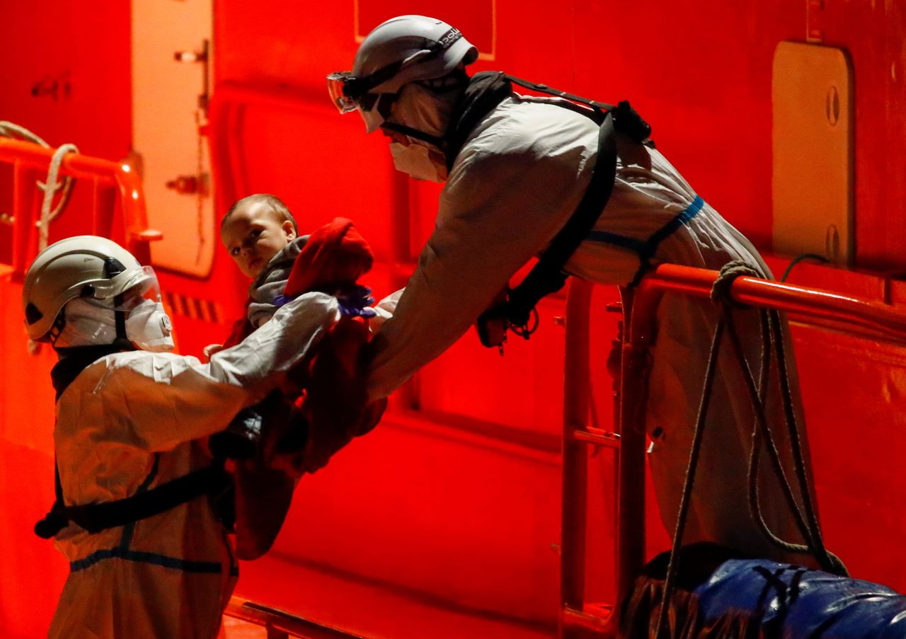 A migrant baby is handed off a Spanish coast guard vessel in the port city of Arguineguin on Monday, March 29.