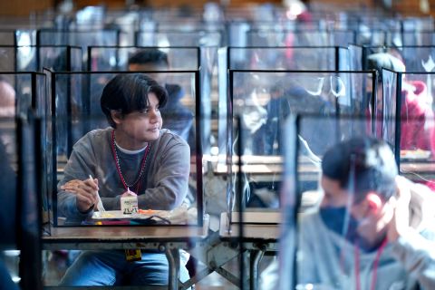 Students are separated by plastic dividers as they eat lunch at Wyandotte County High School in Kansas City, Kansas, on Wednesday, March 31. It was their first day of in-person learning. The district was one of the last in the state to return to the classroom.