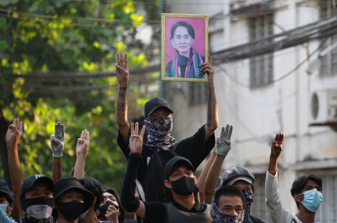 Anti-coup demonstrators raise the three finger of resistance and a portrait of deposed leader Aung San Suu Kyi as prepare to confront police during a protest in Tarmwe township, Yangon on April 1.