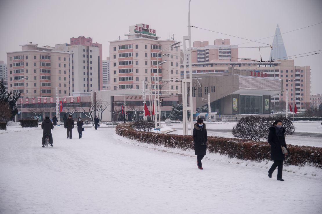 People walk on a snow covered street near the Arch of Triumph in Pyongyang on January 12, 2021. 