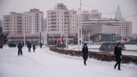 People walk a snow-covered street near the Arc de Triomphe in Pyongyang on January 12, 2021. 