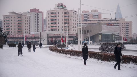 People walk on a snow covered street near the Arch of Triumph in Pyongyang on January 12, 2021.