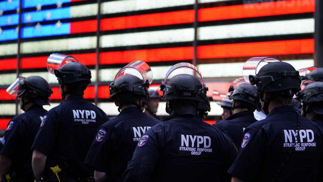 NYPD police officers watch demonstrators in Times Square on June 1, 2020. Protests over the police killing of George Floyd in Minneapolis often forced police departments to pull cops out of high-crime neighborhoods.