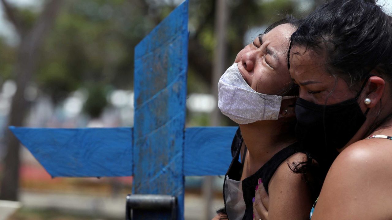 A woman attends the burial of her mother, who passed away due to COVID-19, in Manaus, Brazil.
