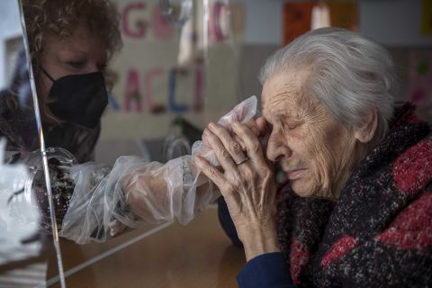 Anna, a resident of the Villa Sacra Famiglia Nursing Home, holds her daughter's hand in the Rome facility's "hug room" on February 24. The room allows residents and their families to touch one another while staying safe from Covid-19.