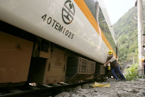 Workers try to remove a part of the derailed train on Saturday.