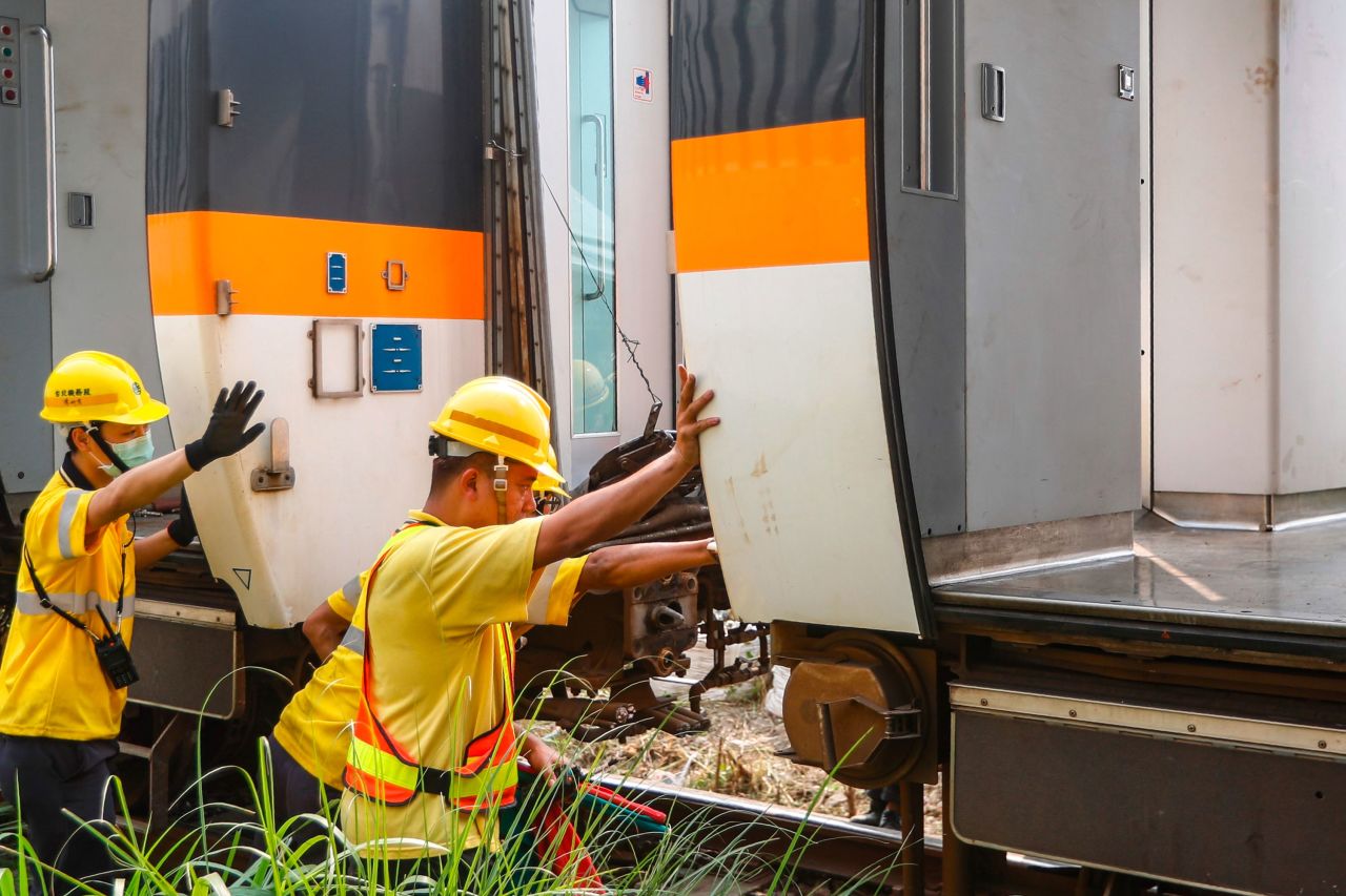 Workers help remove the damaged train carriage.