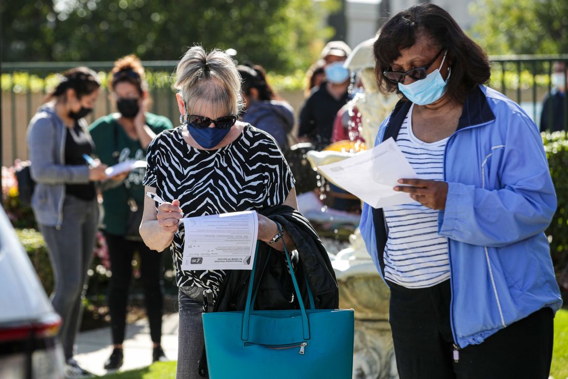 Maureen Brackett, left, and 
Beulah Knowles fill out medical forms while waiting in line for a Covid-19 vaccine at a  clinic held by the LA County Department of Public Health for seniors at Whispering Fountains Senior Living Community on March 31, 2021, in Lakewood, California.