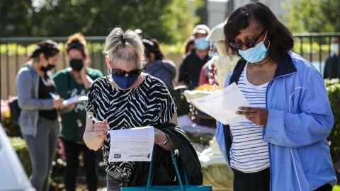 Maureen Brackett, left, and Beulah Knowles fill out medical forms while waiting in line for a Covid-19 vaccine at a  clinic held by the LA County Department of Public Health for seniors at Whispering Fountains Senior Living Community on March 31, 2021, in Lakewood, California.