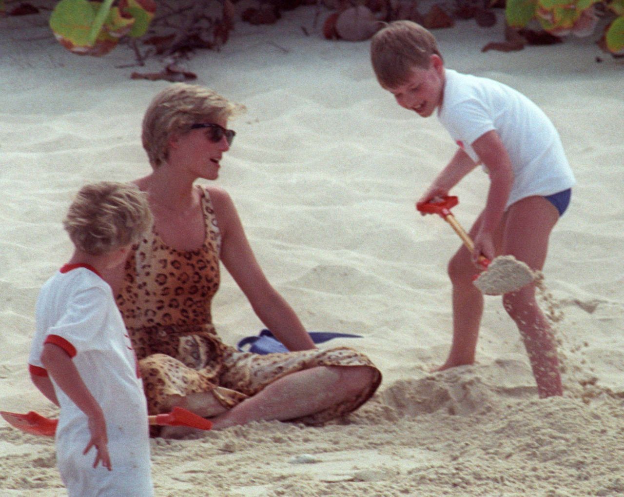 William shovels sand onto his mother while playing on a beach in 1990.